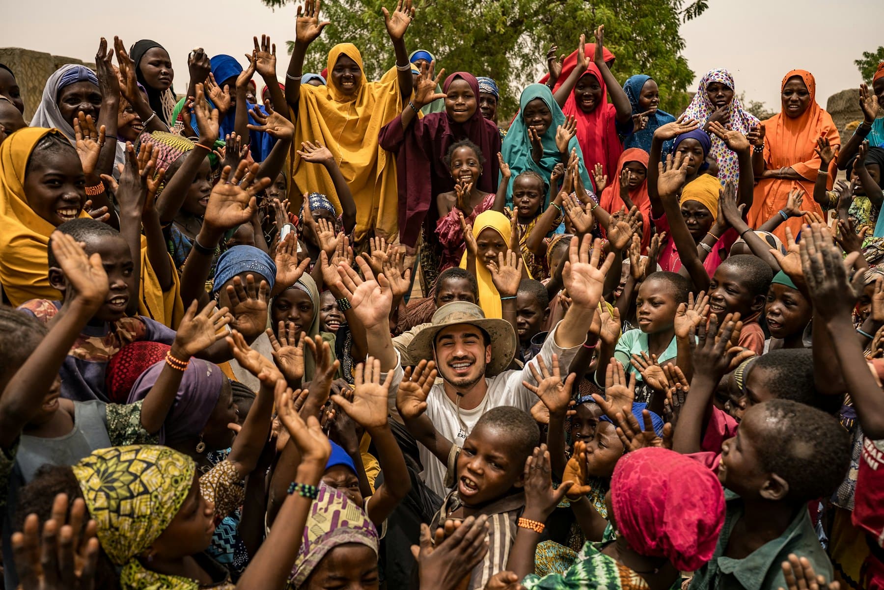 Un large groupe de personnes réunies, bras levés